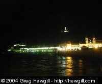 A night view of the dock and municipal hall, with the statue at the top of Mount Urgull in the background.