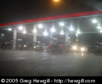 Cars huddled under the protective cover of a gas station during a torrential downpour